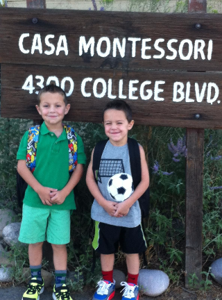 Two Kids Standing in Front of the School Sign
